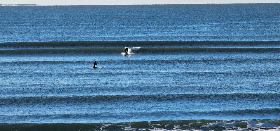 A surfer getting to their feet on a small wave in beatuiful sunny conditions